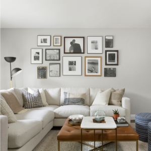A living room with a white sofa and brown coffee table in front of a wall with pictures.